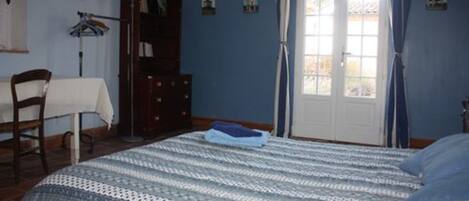 Un dormitorio con cama, cómoda, silla y ventana con cortinas.