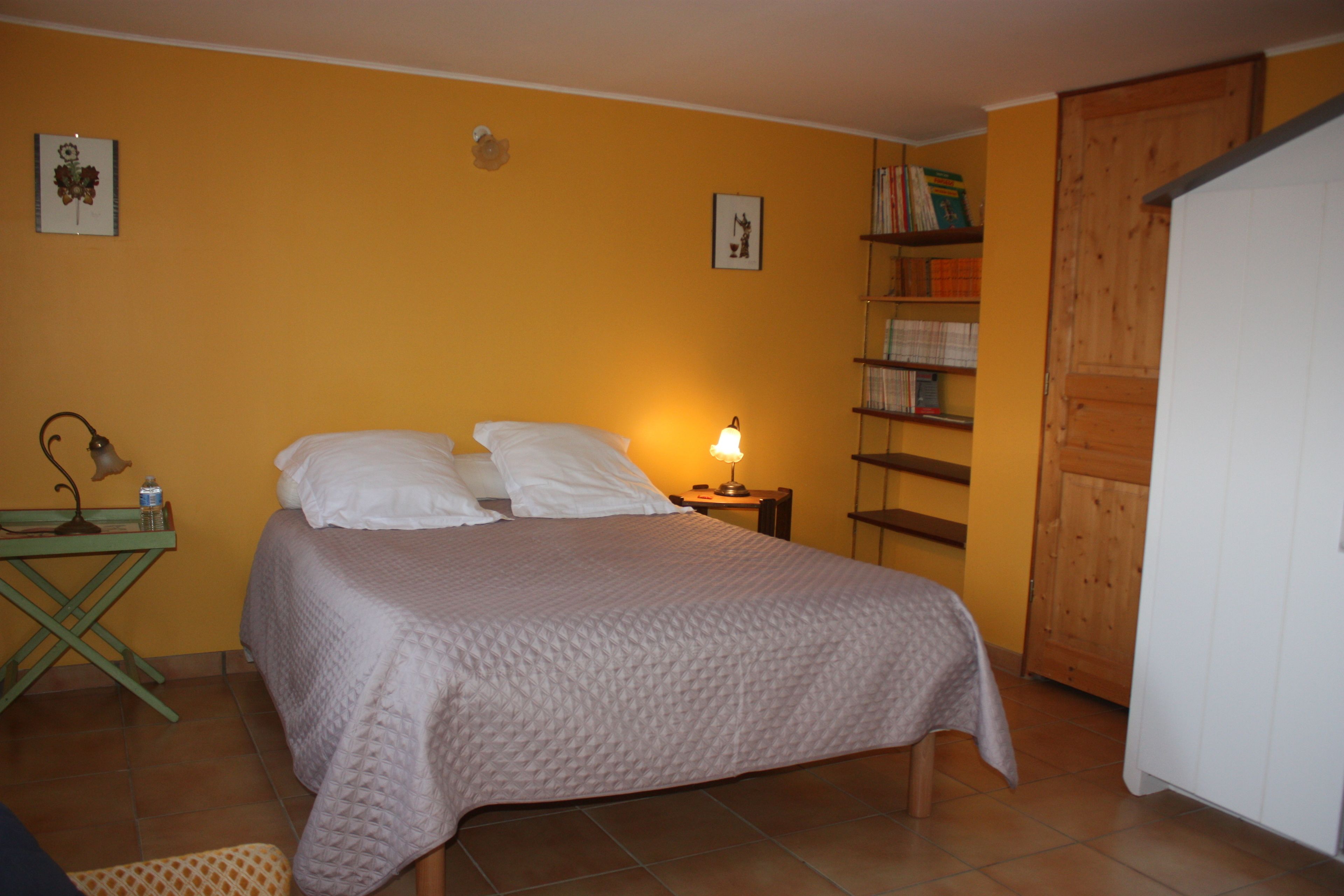 Ein Schlafzimmer mit einem Bett, einem Nachttisch, einer Lampe und einem Holzschrank.