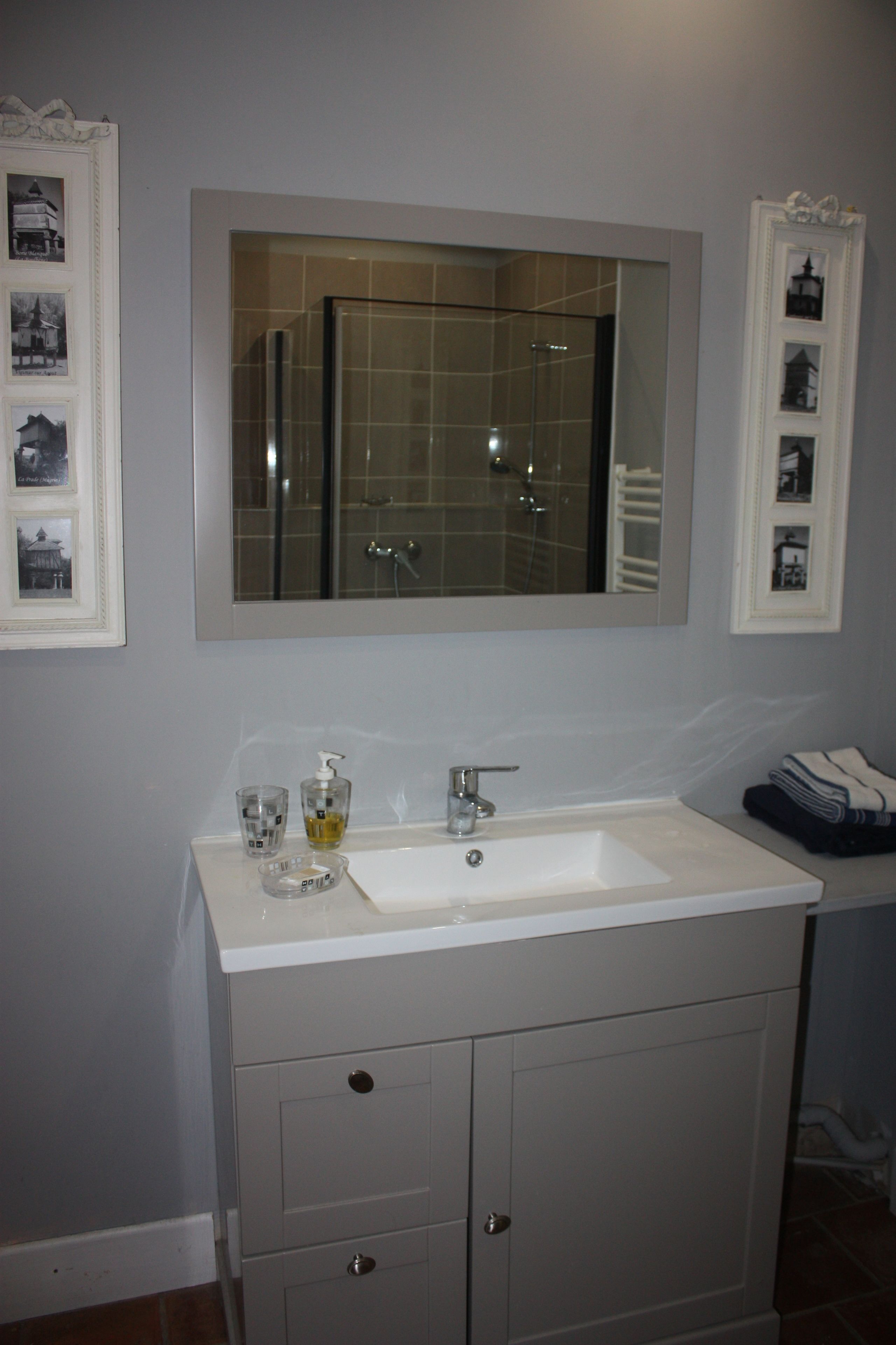 A bathroom with a white sink, a mirror above it, and a glass shower enclosure.