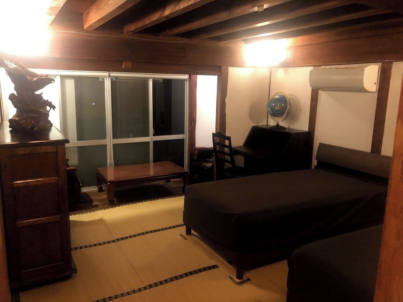 A room with a bed, a desk, a chair, and a window.