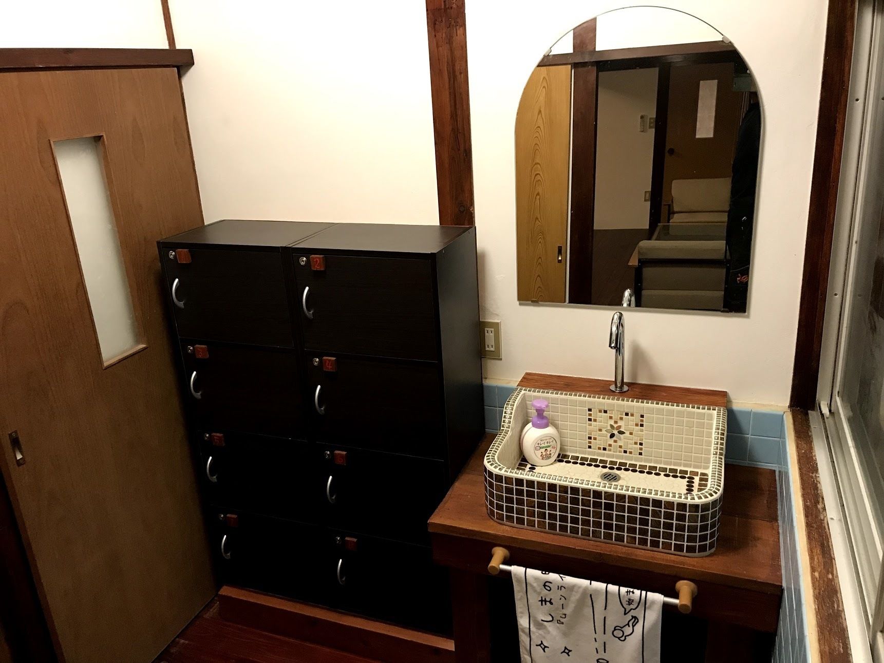 A bathroom with a wooden cabinet, a tiled sink, and a mirror.