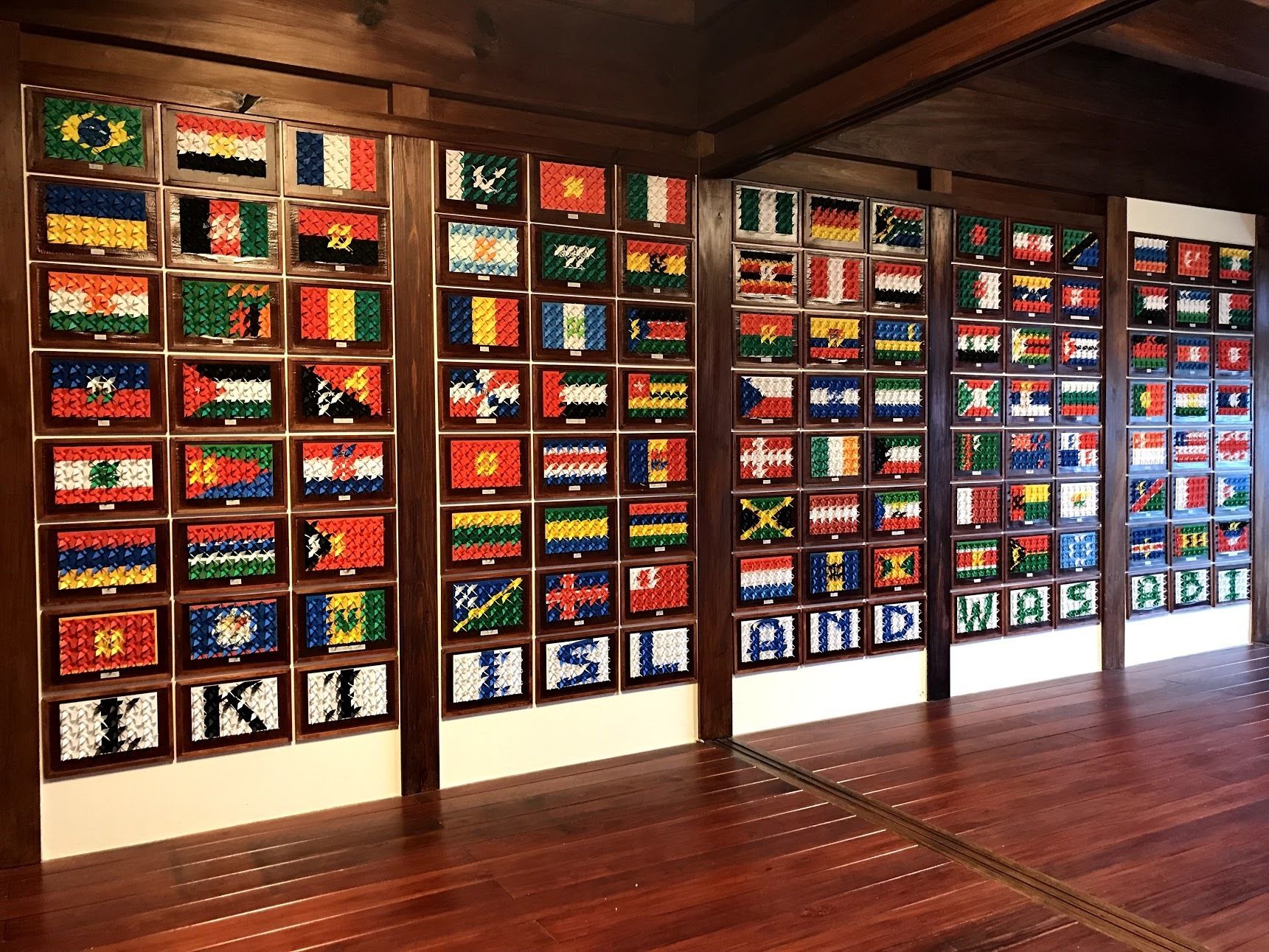A room with wooden floors and walls adorned with framed flags of various countries.