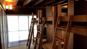 A room with wooden bunk beds, a woven wall, and a window with natural light.