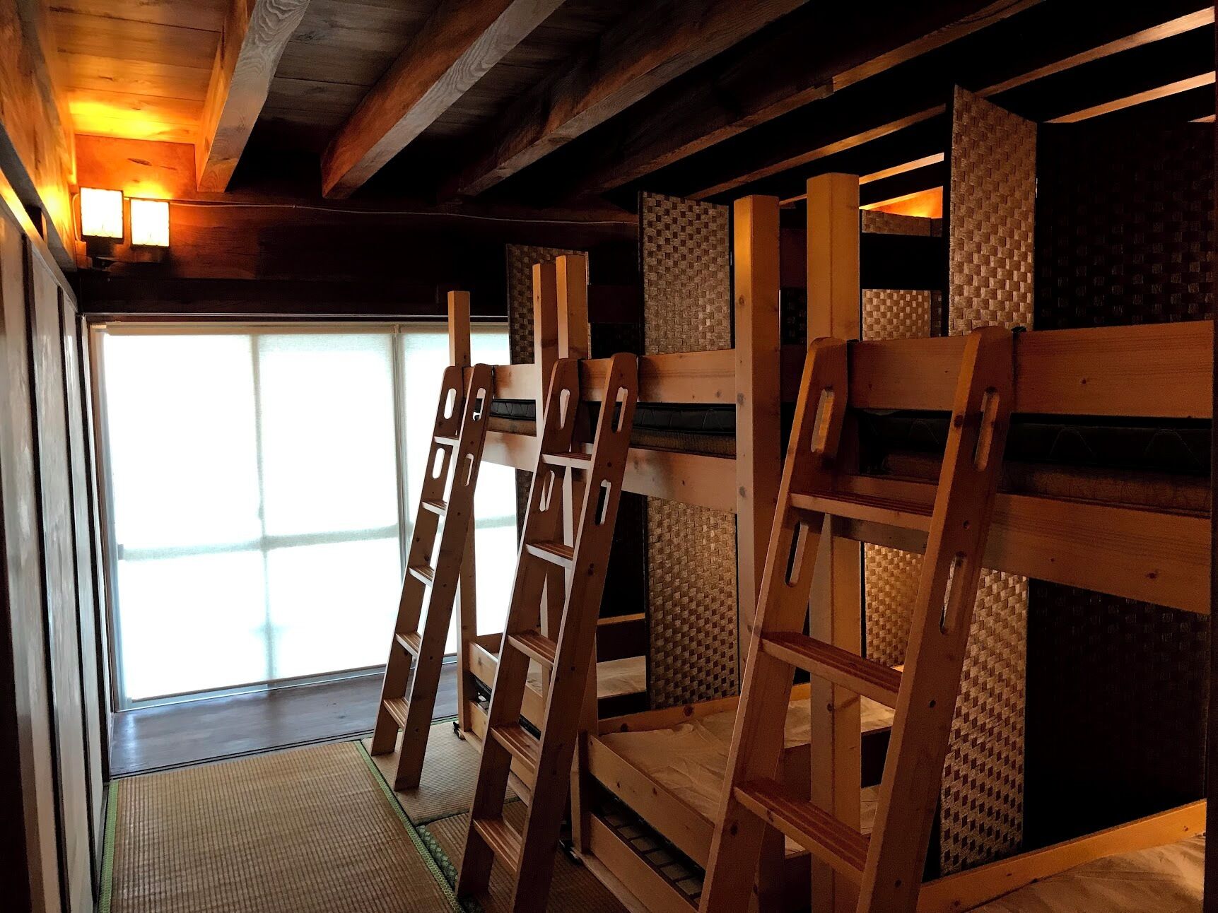 A room with a wooden bunk bed, a ladder, and a woven wall.