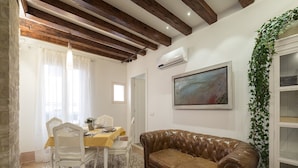 A dining area with a table set for two, a brown leather sofa, and a painting on the wall. - Casa Margherita by Wonderful Italy (Venice)