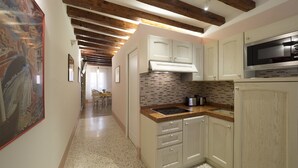 A kitchen with wooden beams, white cabinets, a microwave, and a tiled backsplash. - Casa Margherita by Wonderful Italy (Venice)