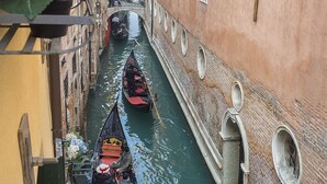 A narrow canal with gondolas, a bridge, and buildings on either side. - Casa Margherita by Wonderful Italy (Venice)