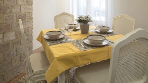 A dining area with a yellow tablecloth, white chairs, and a wooden ceiling. - Casa Margherita by Wonderful Italy (Venice)