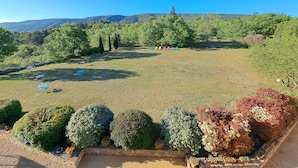 A landscaped garden with neatly trimmed bushes, a clear sky, and distant hills. - Cante Grillet (Lacoste (Provence))
