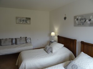 Un dormitorio con dos camas, una mesita de noche con lámpara y adornos en la pared, incluyendo un cartel con la palabra 'Love' y una decoración con forma de corazón.