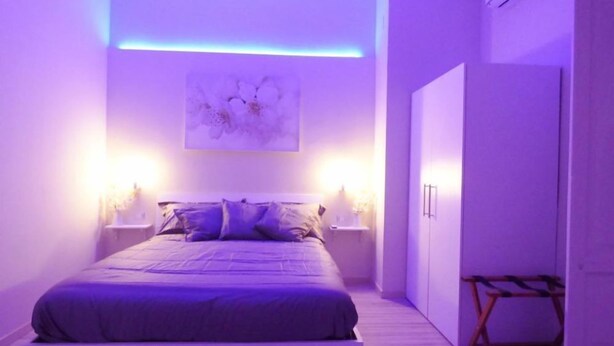 Un dormitorio moderno con una cama, lámparas de noche y una obra de arte en la pared.