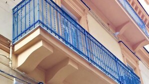 Fachada de edificio con balcón, molduras decorativas y entrada principal.
