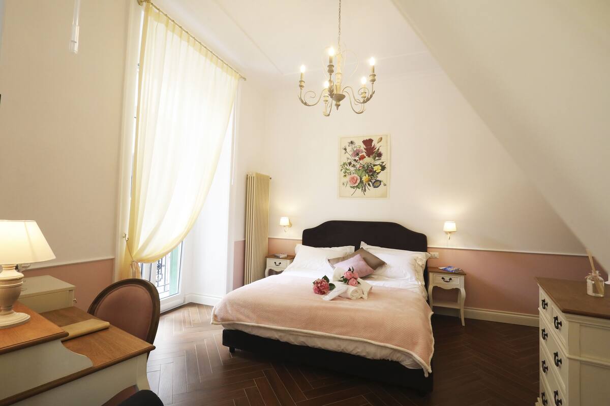 A bedroom with a large bed, bedside tables, a desk, and a chair.