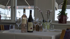 A table set with wine bottles and glasses, a potted plant, and a window with a view. - Samsø Perlen (Samsø)