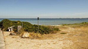 A beach view with a signpost, a path, and a sandy area. - Samsø Perlen (Samsø)