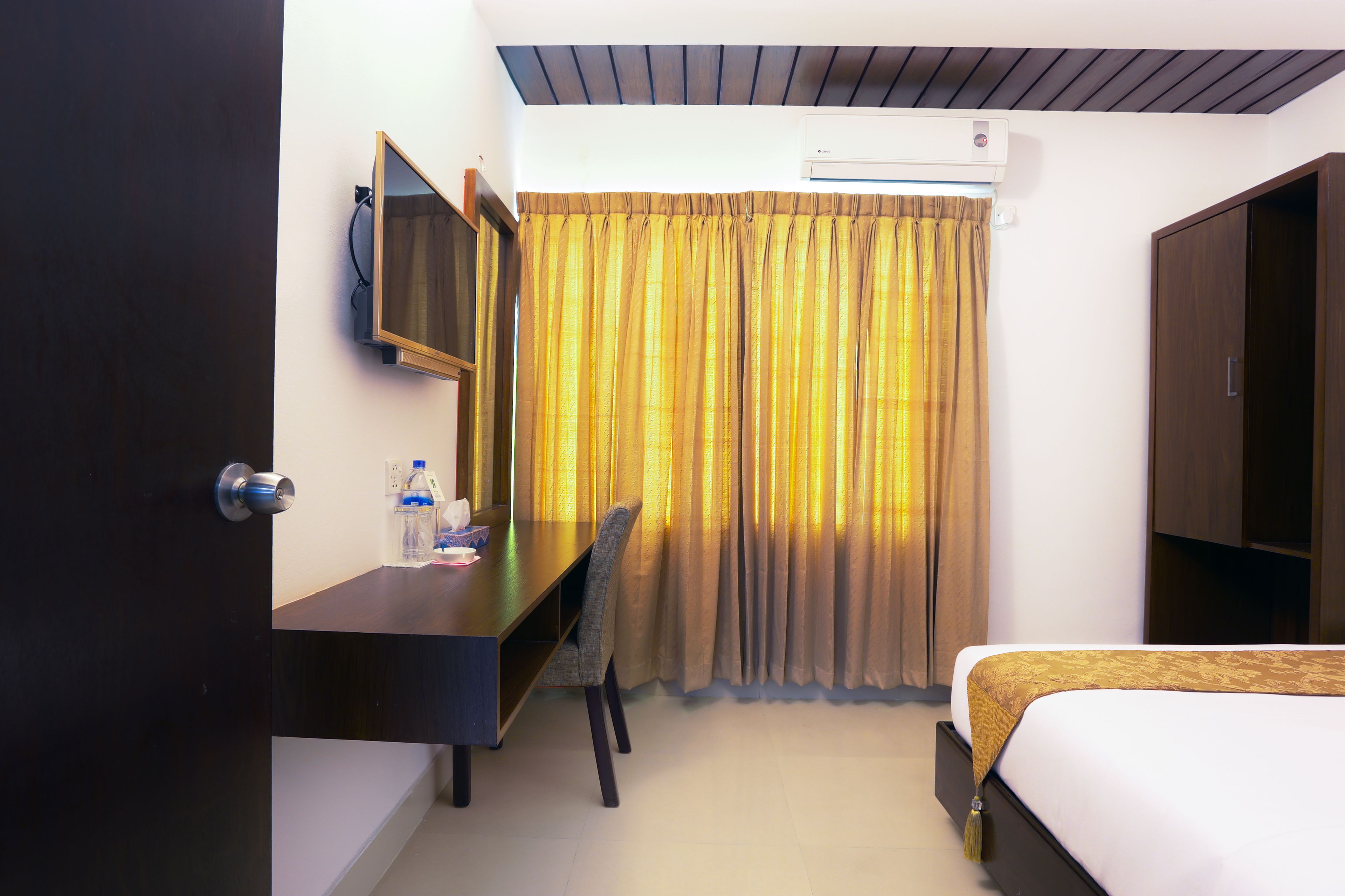 Une chambre d’hôtel comprenant un lit, un bureau avec une chaise, une télévision et une armoire.
