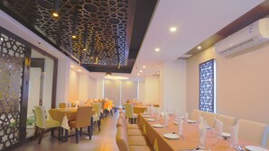 A dining area with multiple tables set for service, chairs, and a decorative ceiling. - Holy Inn (Sylhet)