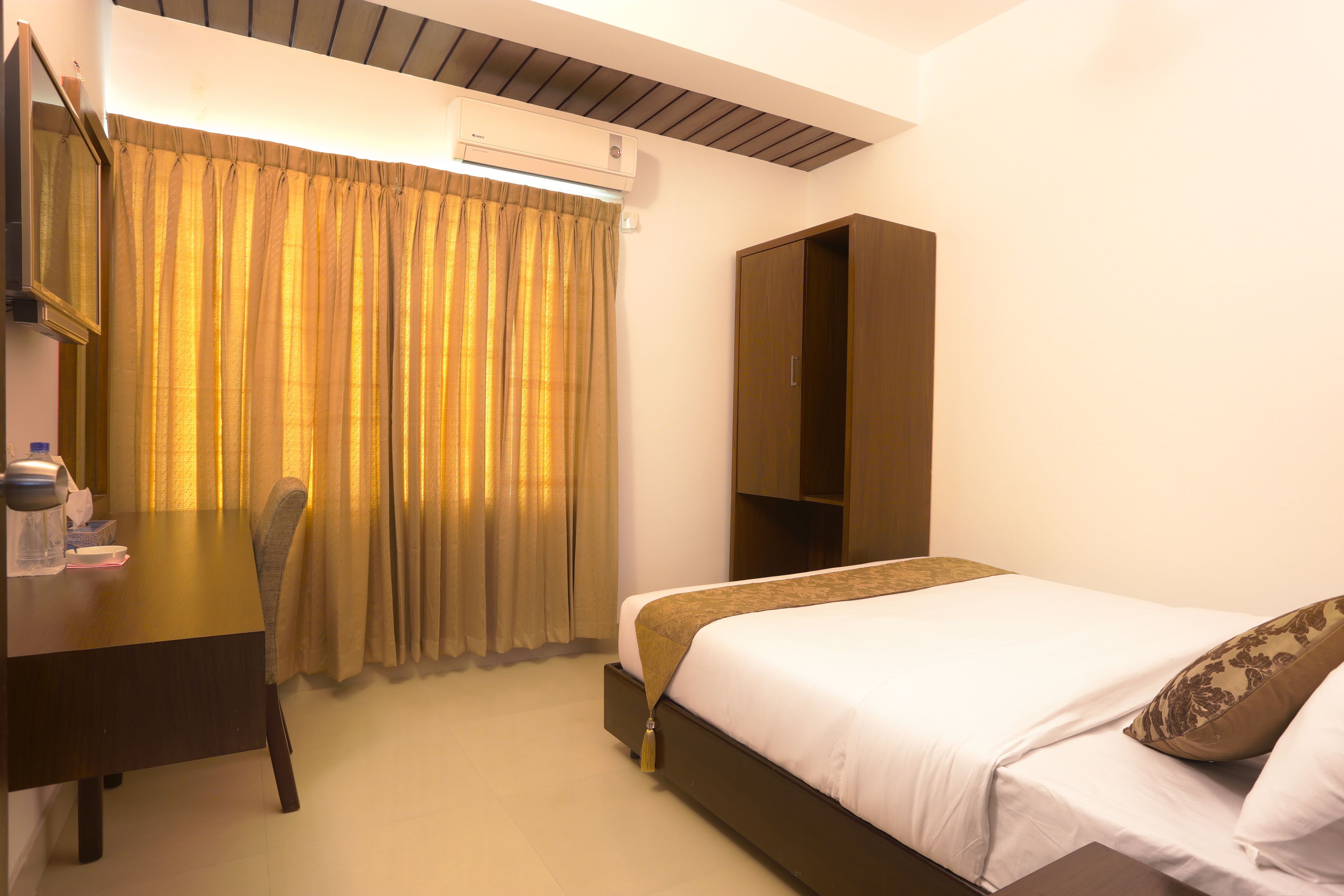 A hotel room with a bed, a desk, a chair, and a wardrobe.