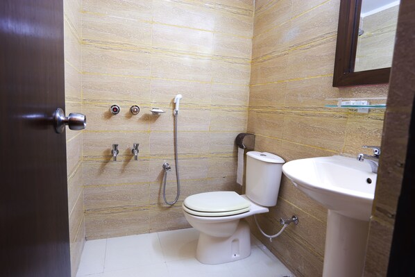 A small bathroom with a toilet, sink, and shower. - Holy Inn (Sylhet)
