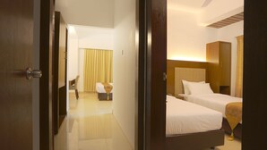 A hotel room with two beds, a wooden headboard, a bedside table, and a chair. - Holy Inn (Sylhet)