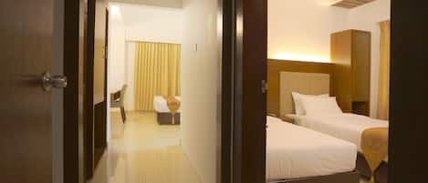 A hotel room with two beds, a wooden headboard, a bedside table, and a chair.