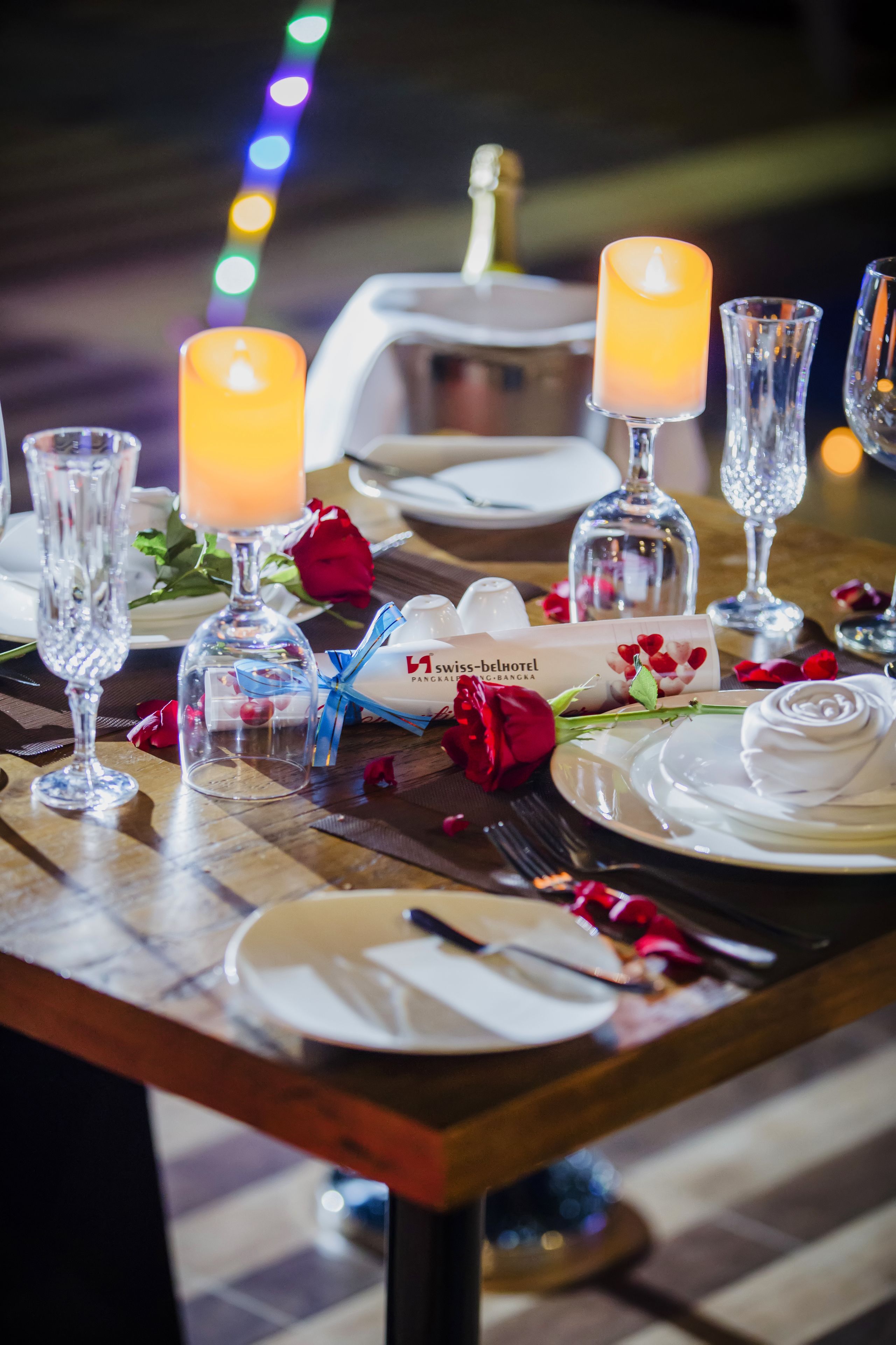 A table set for a meal with candles, a bottle of champagne, and a menu card.