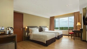 Habitación de hotel con dos camas, un escritorio, una silla, un televisor y una ventana con vistas.