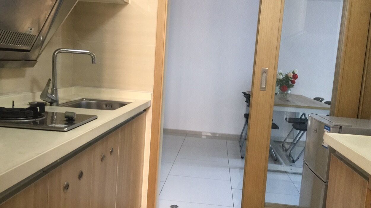 Une cuisine équipée d’un évier en acier inoxydable, d’une cuisinière et de meubles de rangement en bois.