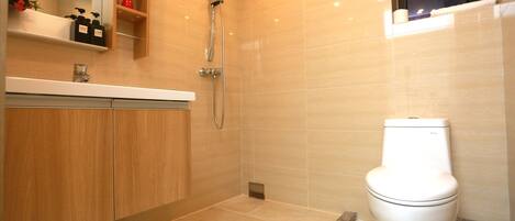 Un baño moderno con ducha, inodoro y armarios de madera.