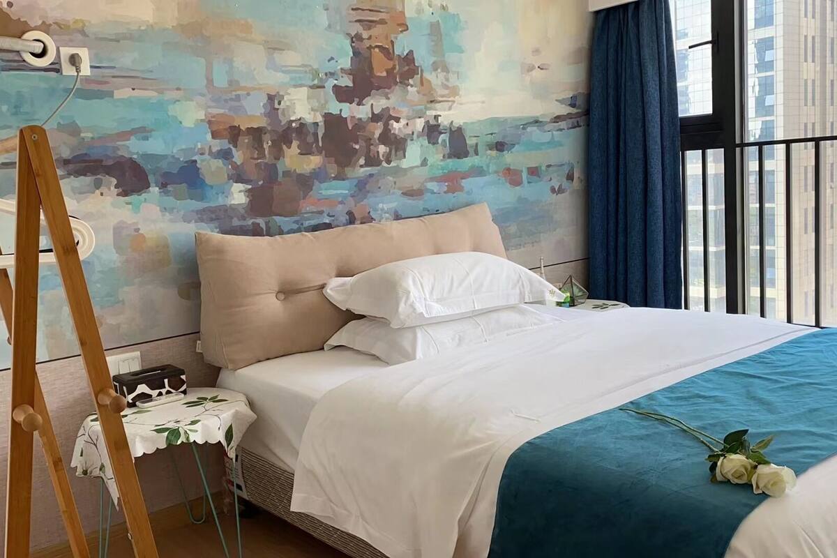 Une chambre d’hôtel moderne avec un grand lit, une petite table recouverte d’une nappe et un tableau accroché au mur.