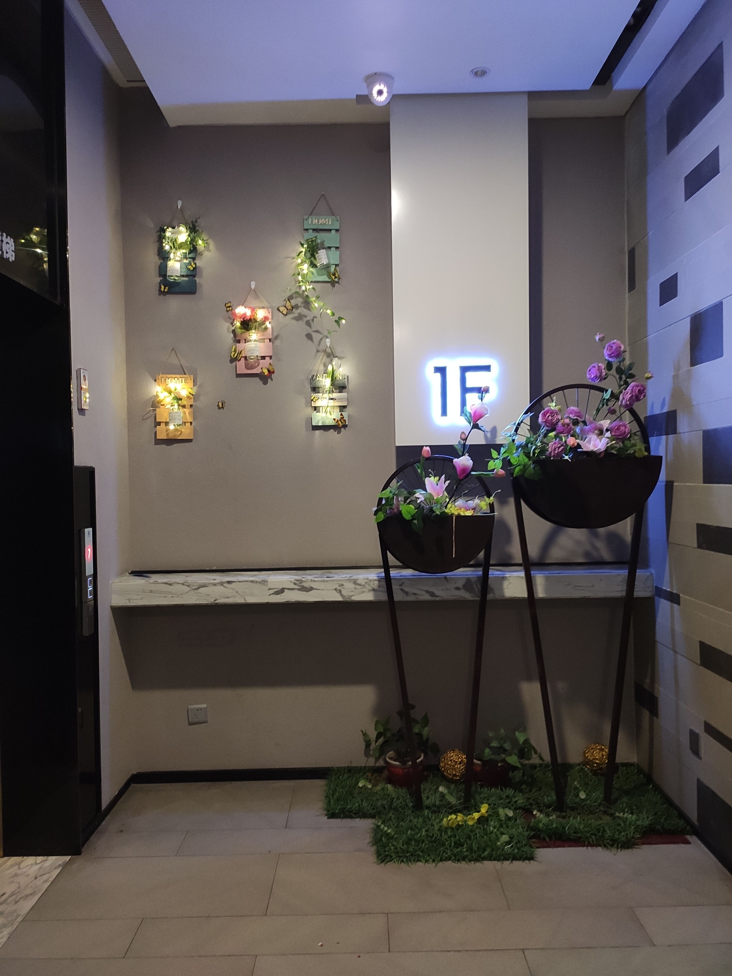 A modern interior with a bench, wall-mounted decorations, and two black plant stands with flowers.