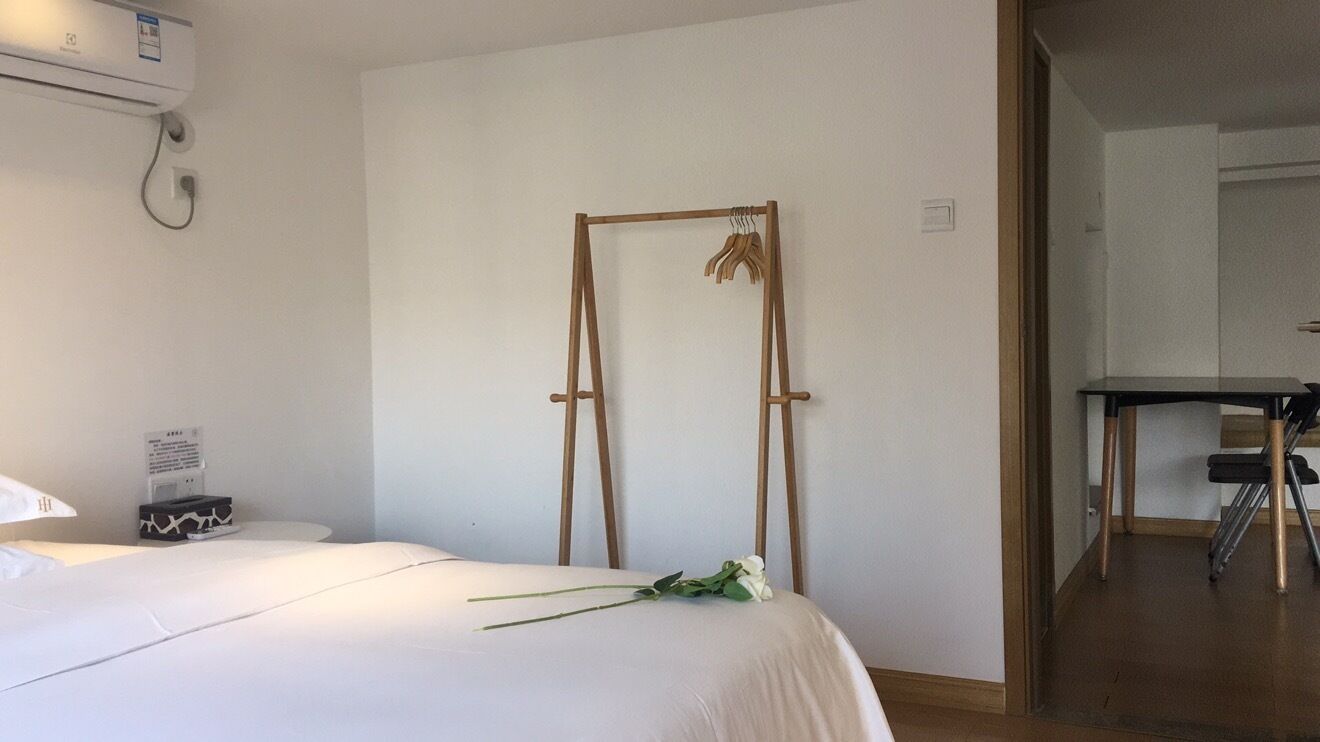 A hotel room with a bed, a wooden drying rack, a desk, and a chair.