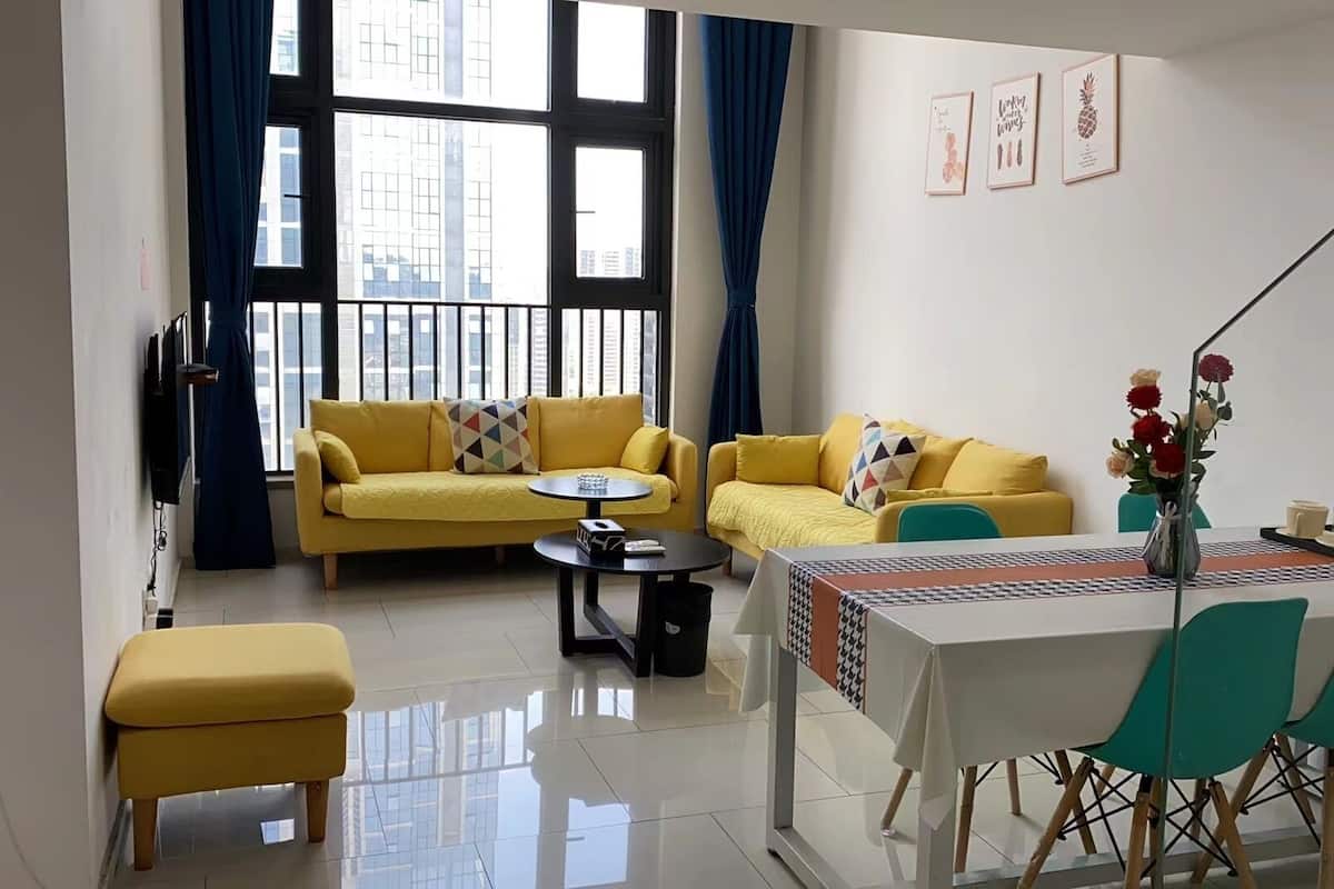 Un salon moderne avec deux canapés jaunes, une table basse et un coin repas comprenant une table et des chaises.
