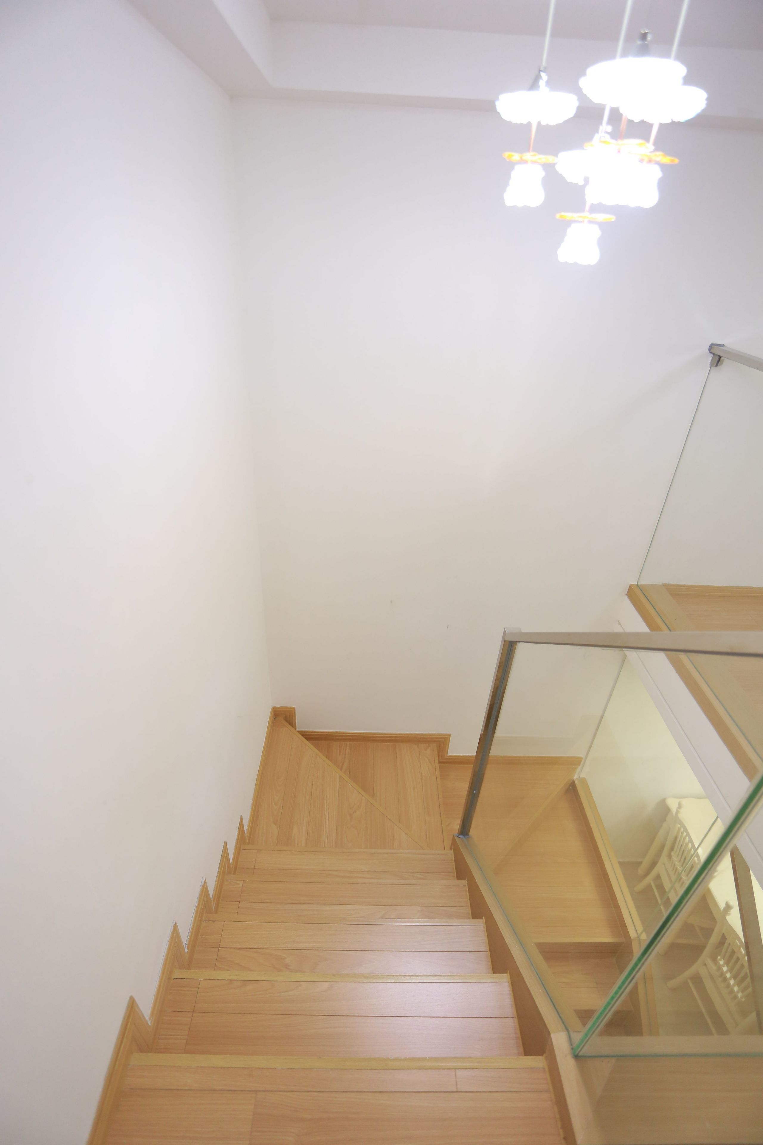 A wooden staircase with glass railings leading to a landing.