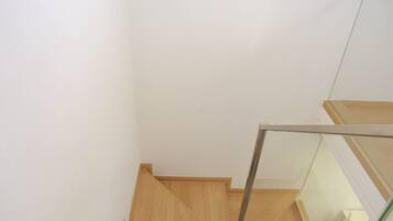 A wooden staircase with glass railings leading to a landing.