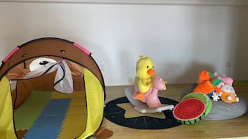 A room with a tent-like play area, a duck toy, and a watermelon toy on a mat.