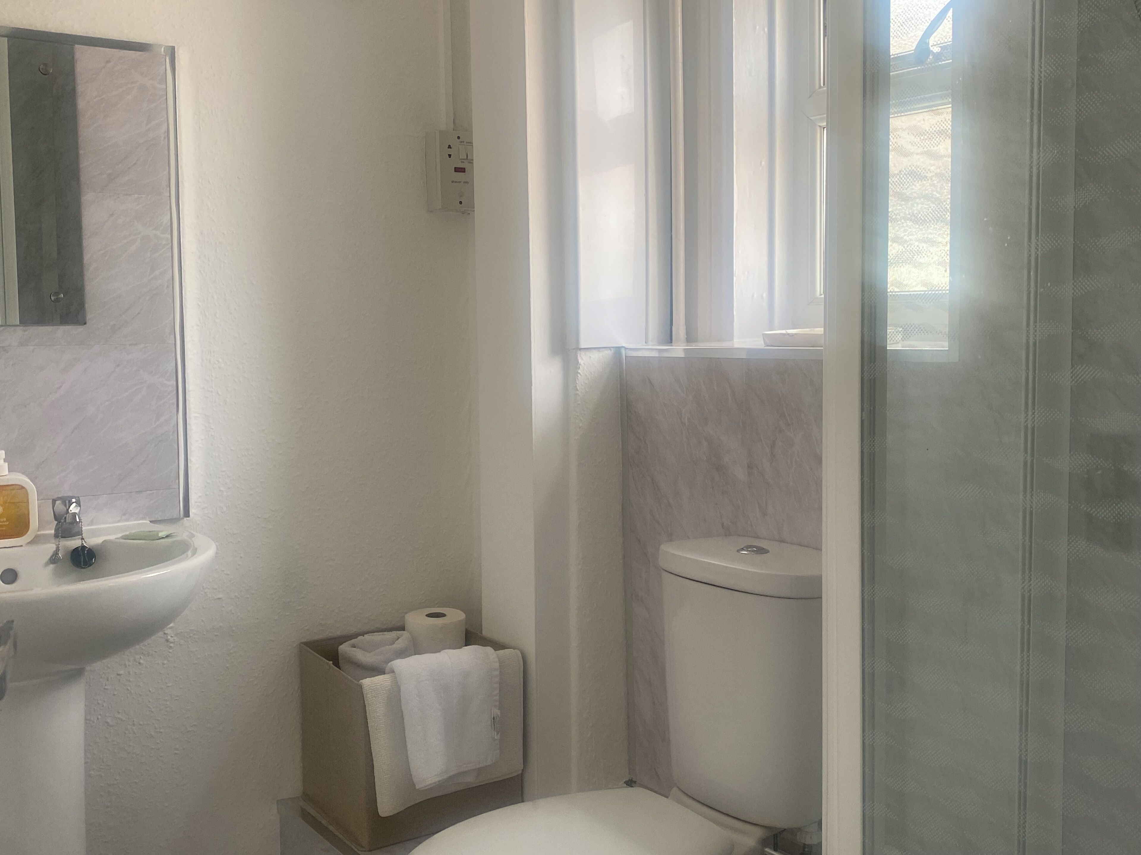 A bathroom with a toilet, a sink, a mirror, and a shower area.