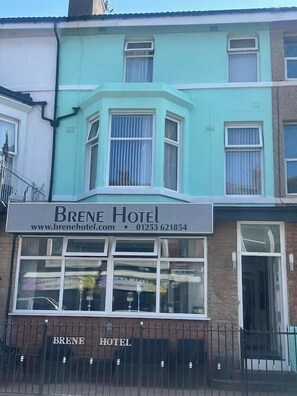 Un hotel con un cartel que muestra el nombre 'Brene Hotel' e información de contacto.