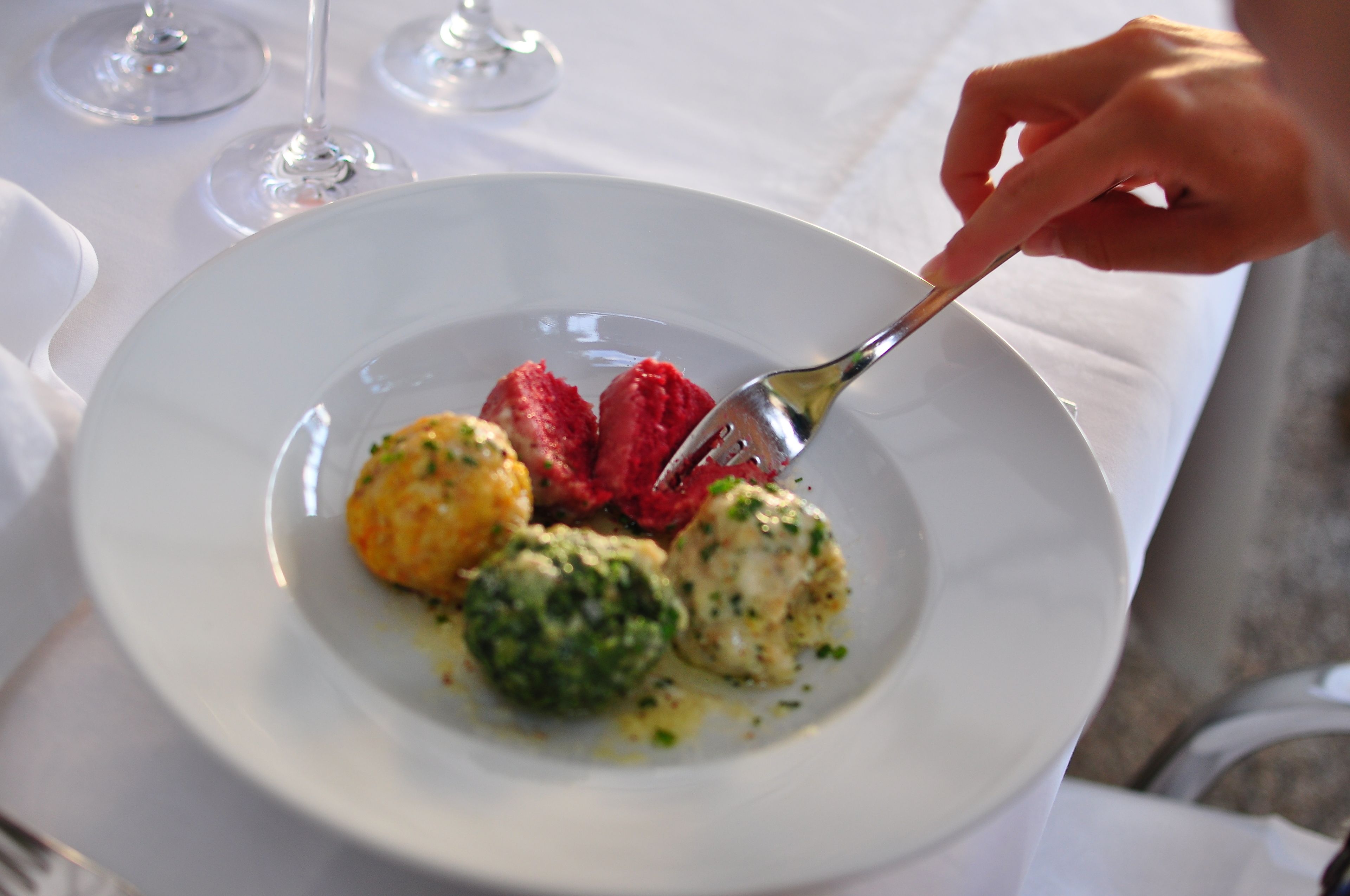 A white plate with a fork, containing a piece of red meat, a green vegetable, and a yellow item, possibly a vegetable or a fruit.