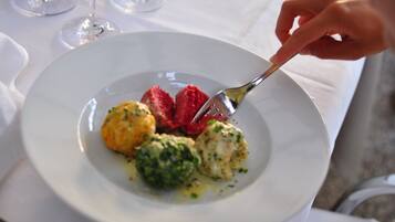 A white plate with a fork, containing a piece of red meat, a green vegetable, and a yellow item, possibly a vegetable or a fruit.
