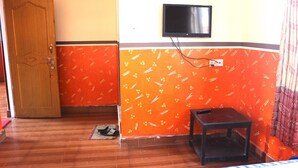 A room with a wooden door, a television mounted on the wall, and a small table. - Hotel Lake Valley (Pokhara)