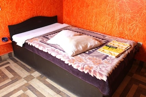 A bed with a dark headboard, a patterned bedspread, and a pillow.