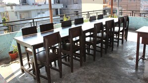A rooftop terrace with a long table and chairs, surrounded by a metal railing, overlooking a residential area. - Hotel Lake Valley (Pokhara)