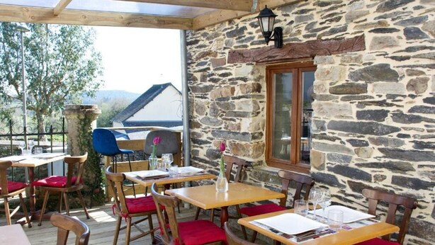 An outdoor dining area with stone walls and wooden tables and chairs. - Valfrescos (Caurel)