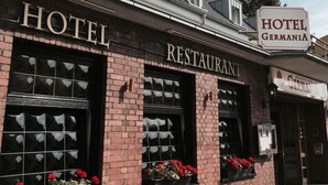 Et hotel med restaurant, med murstensvægge og store vinduer med blomsterkasser.