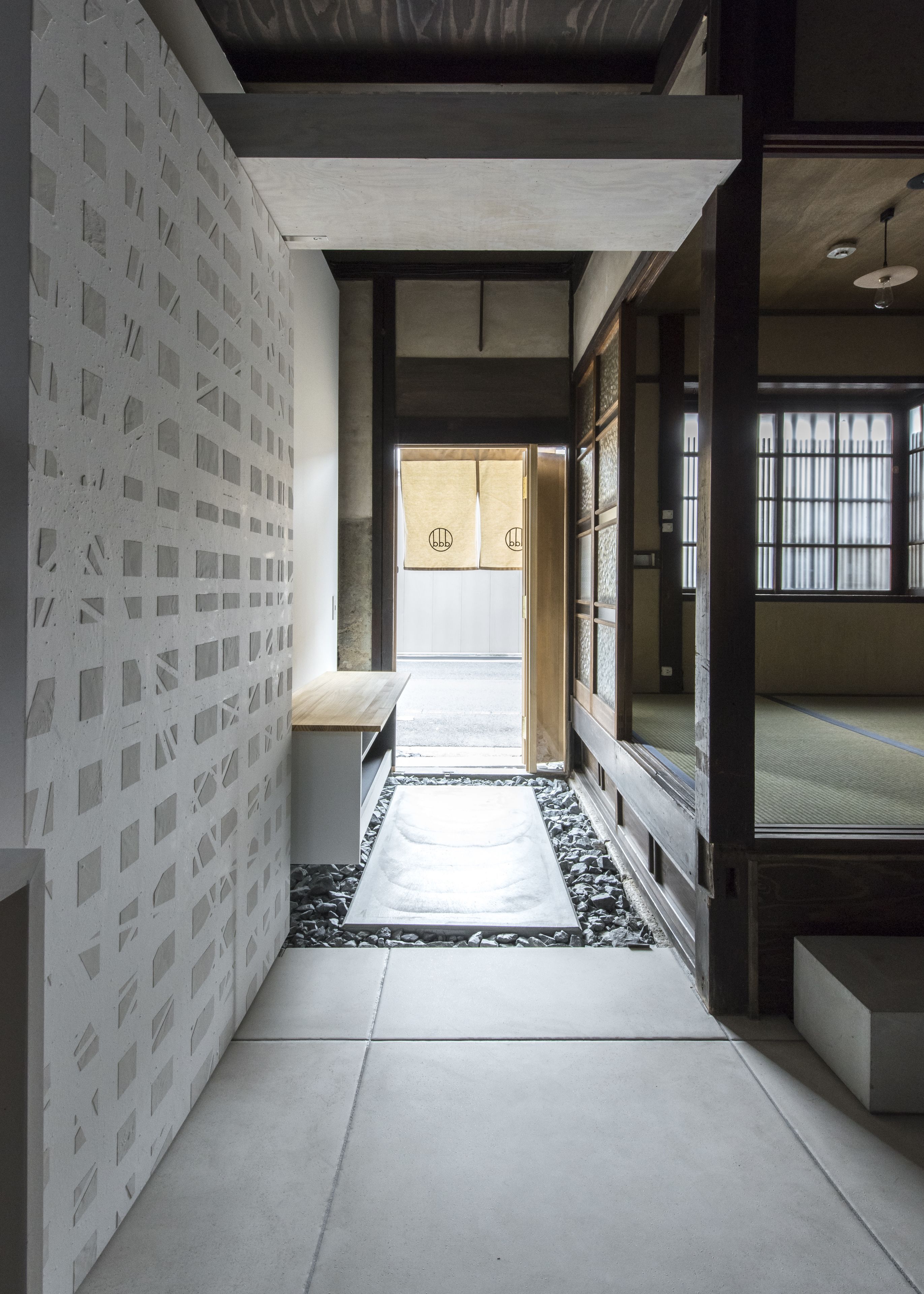 A hallway with a patterned wall, a tatami mat, and a sliding door leading to a room.