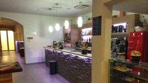 En bar med en stenbordplade, reoler med flasker og en glasmontre med snacks.
