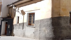 Un edificio con fachada desgastada, una ventana con barrotes y una puerta con el número 6.