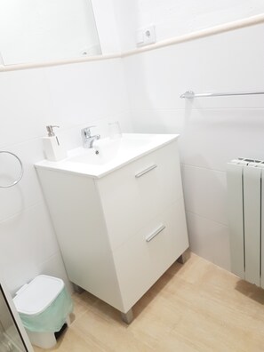 Un baño pequeño y moderno con un lavamanos blanco, dos cajones, un inodoro y un perchero para toallas.