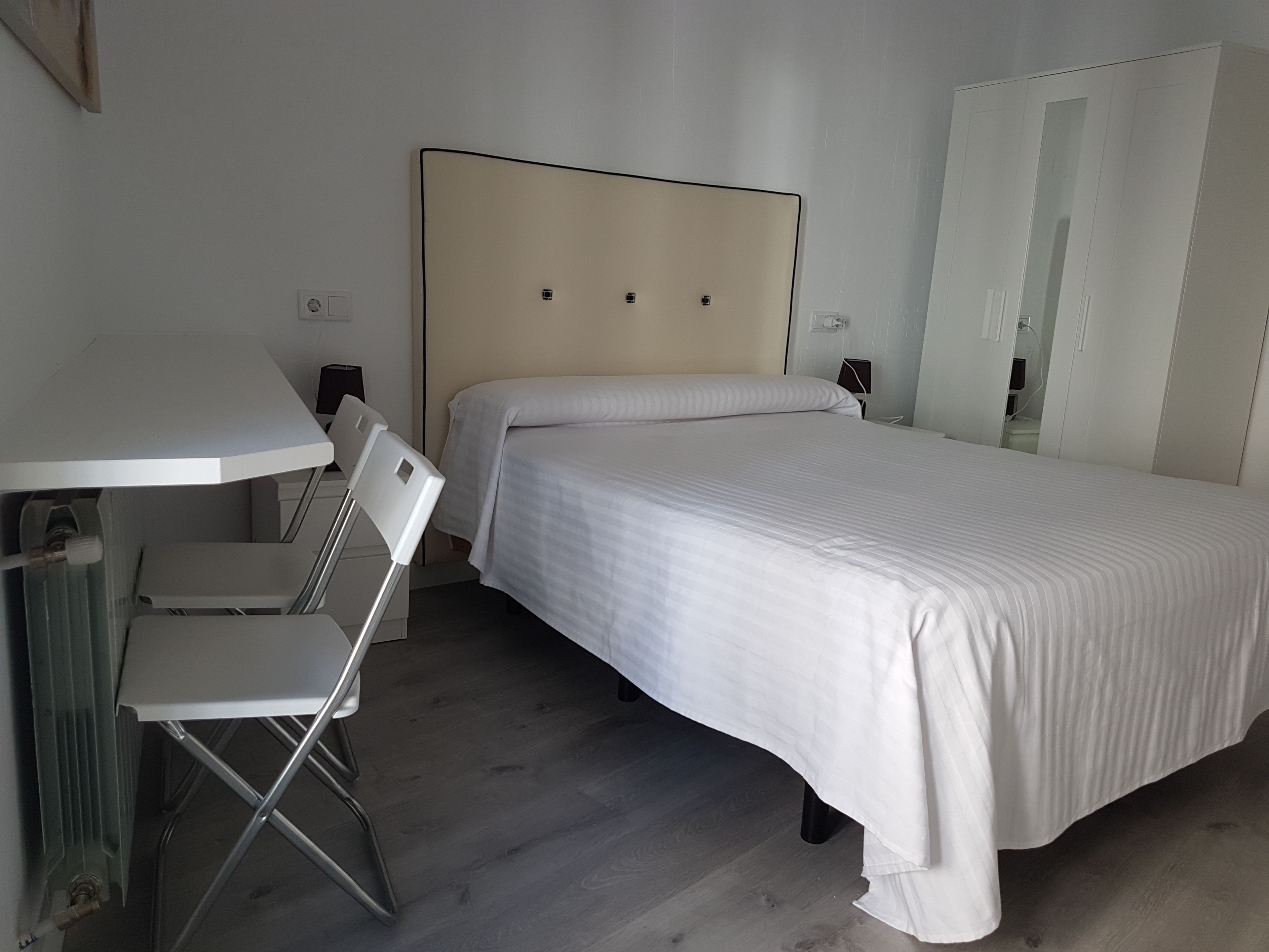 Quarto com cama, escrivaninha e cadeira.